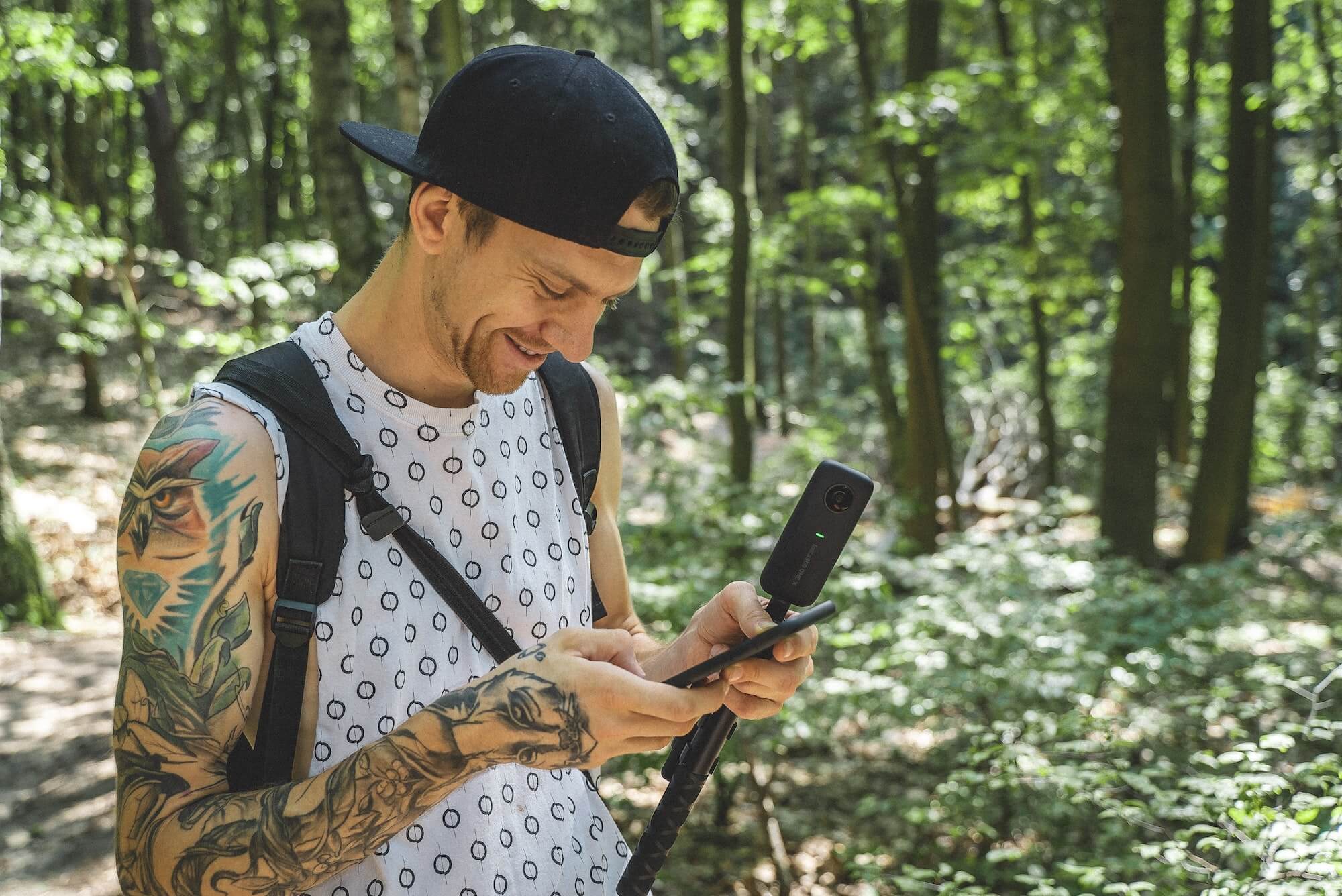 Creator looking at their footage on their camera in a forest